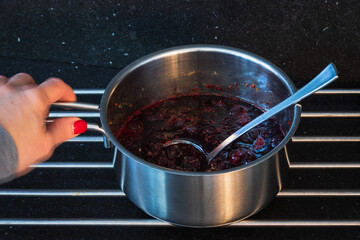Making jam of red berries on a metal cooking pot