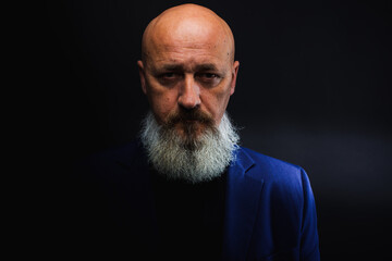 Close-up image of serious brutal bearded man on dark background Confident and dramatic concept