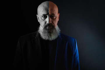 close up photo, portrait of a serious, thoughtful, bearded man on a dark background confident and...