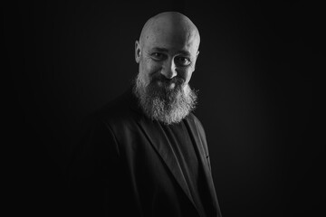 Fototapeta premium close up photo, portrait of a serious, thoughtful, bearded man on a dark background confident and dramatic looking straight. Concept of male portrait. Black and white photo. Low key