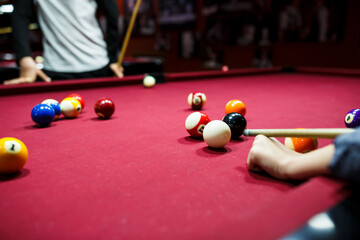 Boy plays billiard or pool in club. Teenager learns to play snooker. billiard cue strikes the ball on table. Active Leisure, sport, hobby concept