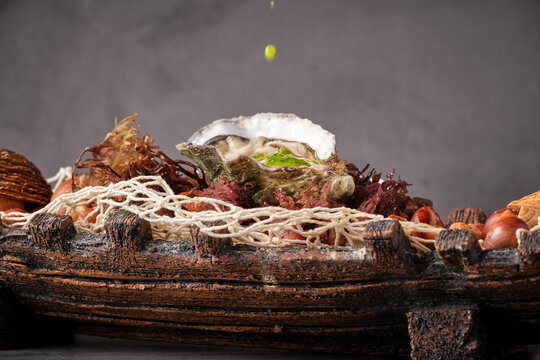 Closeup of palatable oyster in shell served in plate with various seafood ingredients in Asian restaurant