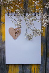 Valentine's day background with wooden beautiful heart and white flowers on yellow background