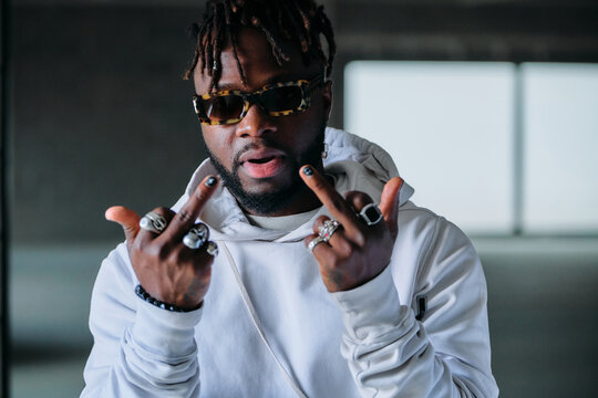 Expressive African American male in fancy outfit showing tongue and middle fingers while looking at camera