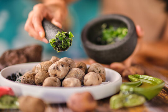 Crop unrecognizable chef crushing spices in pounder with pestle above cooked potatoes