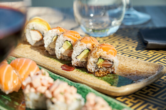 Sets of assorted sushi and rolls served on table in Asian restaurant - Powered by Adobe