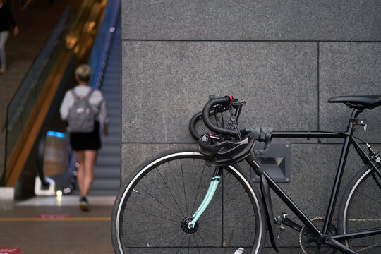 Bicycle standing near building on blurry background of walking woman in afternoon