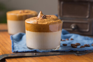 Delicious Dalgona beverage with foam garnished with chocolate and placed on table with coffee grains and napkin in cozy cafe