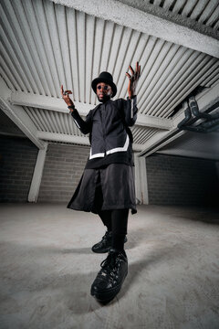 Low Angle Of African American Male Hip Hop Dancer In Black Apparel Rehearsing In Underground Garage And Showing Choreography Movements