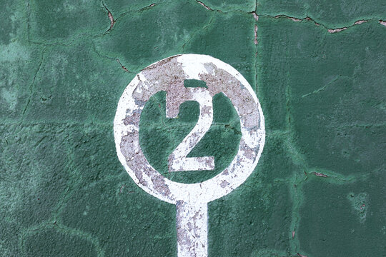 Weathered green wall with peeling paint and number two showing concept of winner