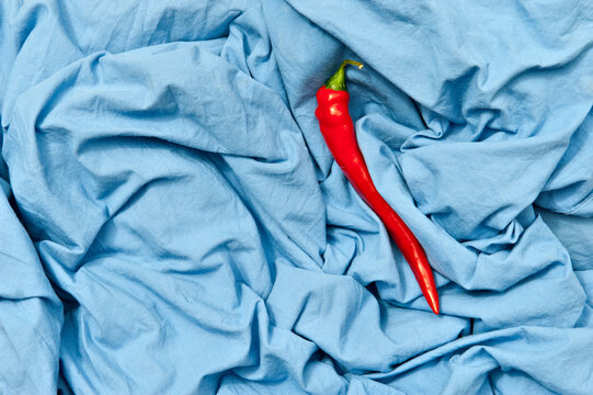 Overhead view of bright hot pepper with shiny peel on creased blue textile