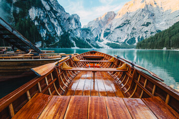 Wooden boat with paddles floating on turquoise water of calm lake on background of majestic landscape of highlands