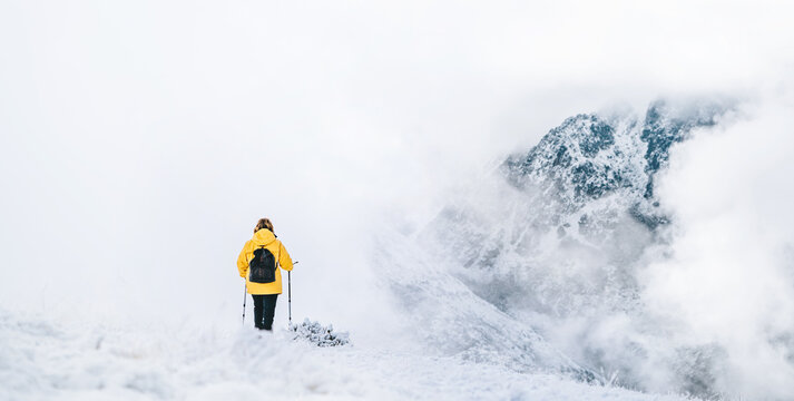 Back view of anonymous hiker with trekking poles walking on snowy ground in Pyrenees mountains in Andorra