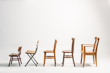 Profile of five old wooden chairs against white background