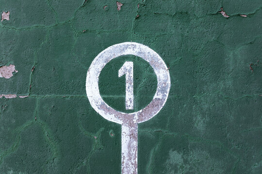Weathered green wall with peeling paint and number one showing concept of winner