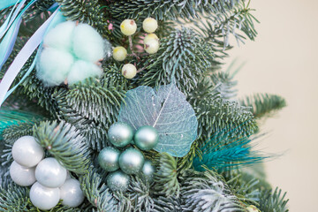 Christmas decorations for home comfort. Gift box with fir, christmas tree branches and New Year's toys in a turquoise hat box. Girl in mittens holds gift for New Year ivent. Background