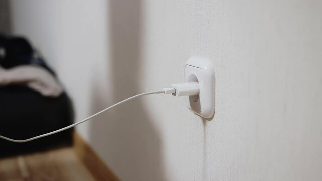 girl with long nails inserts and takes out a charger. female plugs and unplugs the charger into an electrical outlet