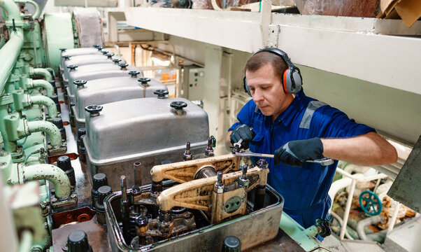 Marine engineer officer reparing vessel engines and propulsion in engine control room ECR. Ship onboard maintenance