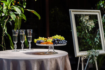 Basket with fruit and glasses with champagne outside.