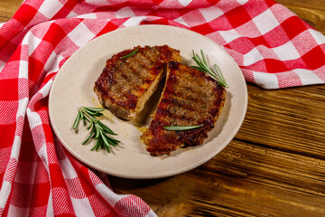 Grilled pork steaks with rosemary on wooden table