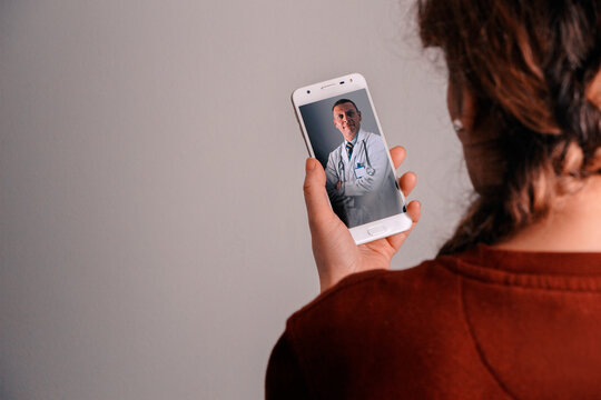 Mujer viendo telefono móvil en una videollamada con un medico. Distanciamiento social. Telellamada. Llamada por zoom. telemedicina. Video call