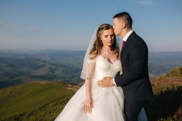Wedding couple in mountains. Bride and groom standing on the hill