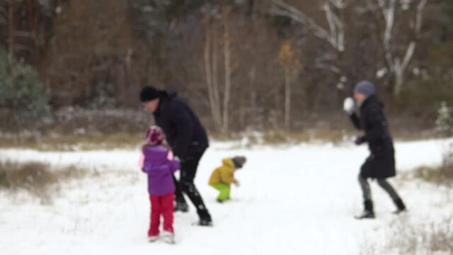 Blurred background.Blurred image of a family of four: mom, dad, son and daughter are playing snowballs in nature. Camping with the family.4k