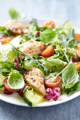 Salad with Chicken Breast, Cherry Tomatoes, Cucumber, Rocket and fresh Basil. Bright wooden background. Close up.