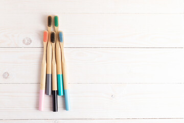 Multicolored bamboo toothbrushes on a white wooden table ..