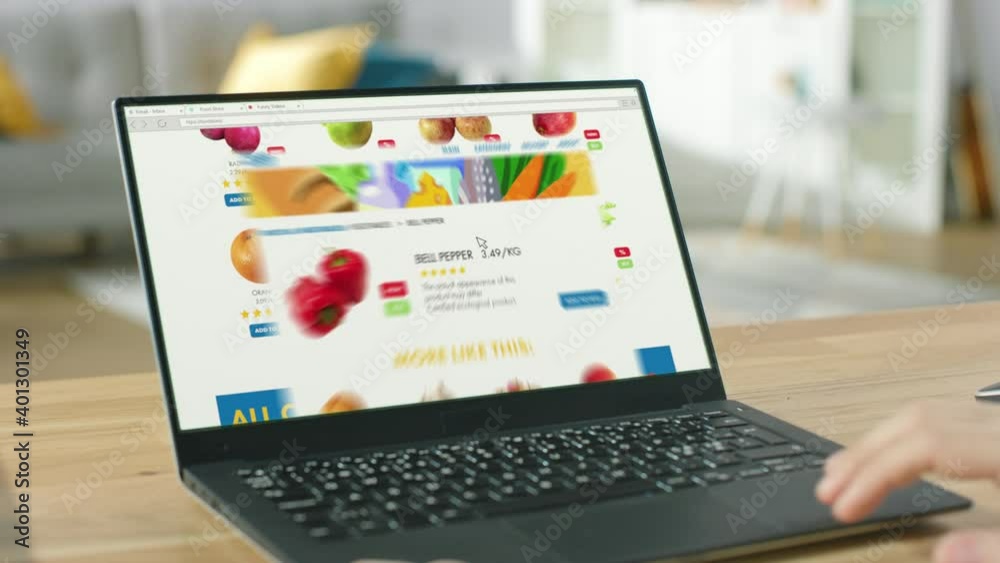 Wall mural person uses laptop computer browsing through online food delivery market, choosing vegetables in fre