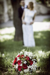 Wedding flowers in the foreground and bride and groom blurred in the background. Wedding photo of...