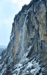 Obraz na płótnie Canvas Huge waterfall falling from a tall, sharp cliff. The rocky high abrupt is has snow on its cliffs. Swiss Alps, Lauterbrunnen.