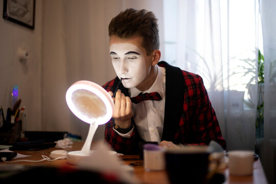 mime artist paints lips in front of a mirror