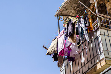 Multicolored laundry is dried on strings on an old balcony in the old city of Jerusalem
