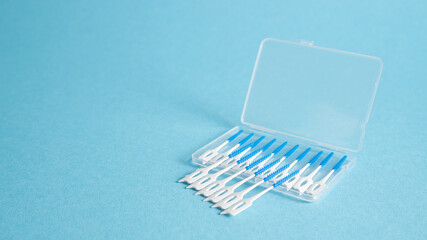 Interdental brush stick in box on blue background. Dental cleaning tools. Teeth toothpicks. Dental floss picks 