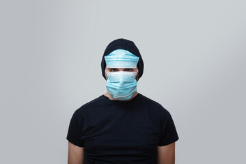 young man wearing a lot of face protective medical masks for protection from virus disease over grey background