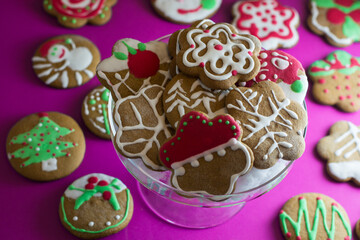 Christmas gingerbread cookies beautifully decorated and assorted on a pink background. 