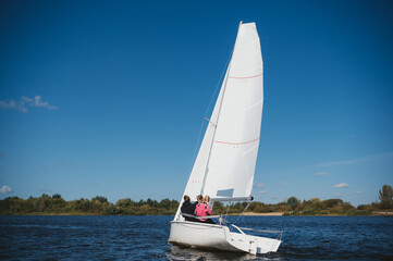 A beautiful white yacht is sailing in the wind on the river against the background of a beautiful...