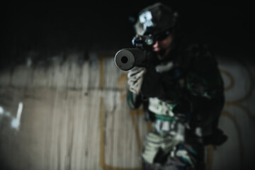 Soldier in full US MARSOC armed with assault rifle run through the abandoned building. Military...