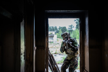 Fototapeta na wymiar Soldier in full US MARSOC equipment entering abandoned building, aiming different angles with MK18 assault rifle