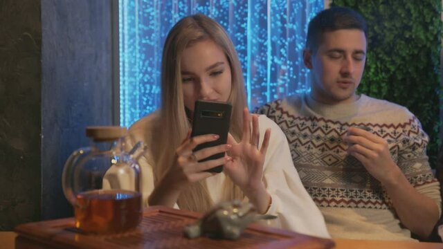 Young woman takes a photo of chinese tea ceramic frog in traditional tea cafe
