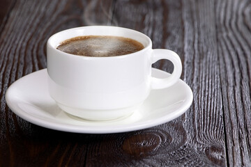 A cup of coffee on a wooden background. Morning hot coffee on a wooden table. A white coffee cup. Steam.Espresso