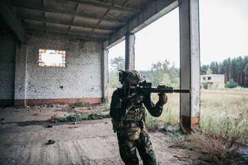 Soldier in full US MARSOC armed with assault rifle run through the abandoned building. Military...