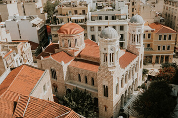 Aerial view of old orthodox cathedral surrouned by old houses in old town of Athens during sunny day.