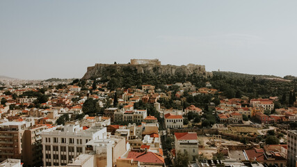 Aerial tilt up shot of Athens city buildings and Acropolis Architecture in background during sunny day in Athens,Greece.