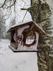 wooden birdhouse with snow hung on a tree in the winter season