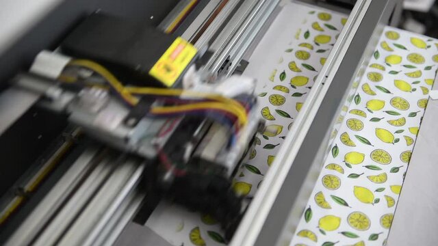 Close up view of working mainting machine that making lemon and leaves pictures on white cloth.