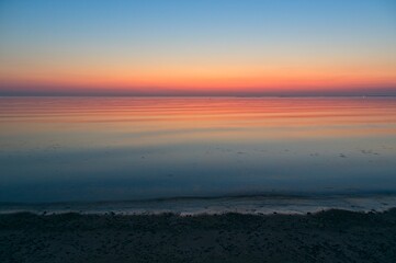 Sunrise at the beach with sand and small rocks.