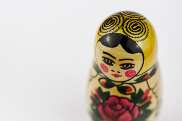 A traditional painted Russian wooden doll in a white studio from an angle.
