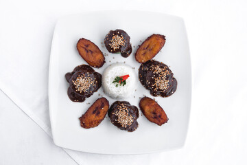 Mexican mole, chicken rolls with Mexican mole, sesame, rice and fried plantain on white background